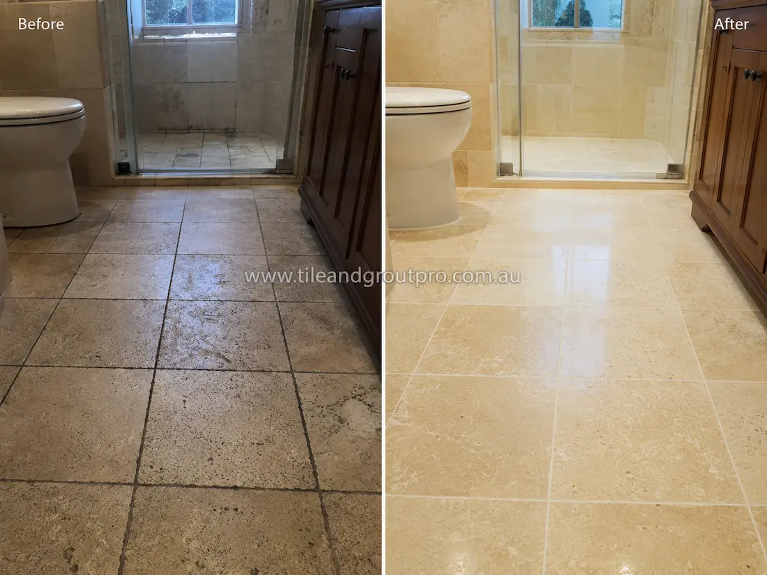Before tile renewal, the travertine bathroom floor tiles and shower area showed dark grout lines, soap residue, and surface dullness in a residential bathroom.