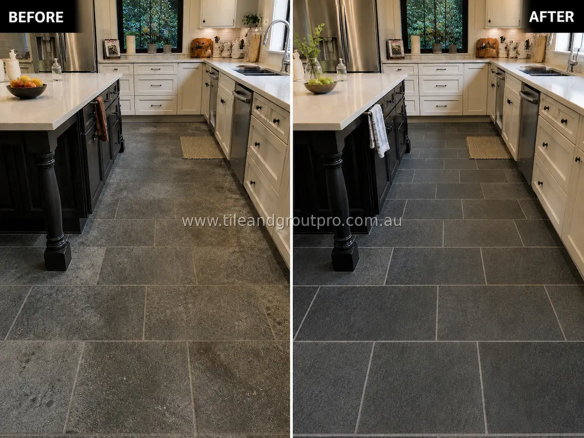 Bluestone natural stone kitchen floor tiles between white cabinets and island with visible dirt buildup, dull finish, and darkened grout before tile and grout cleaning