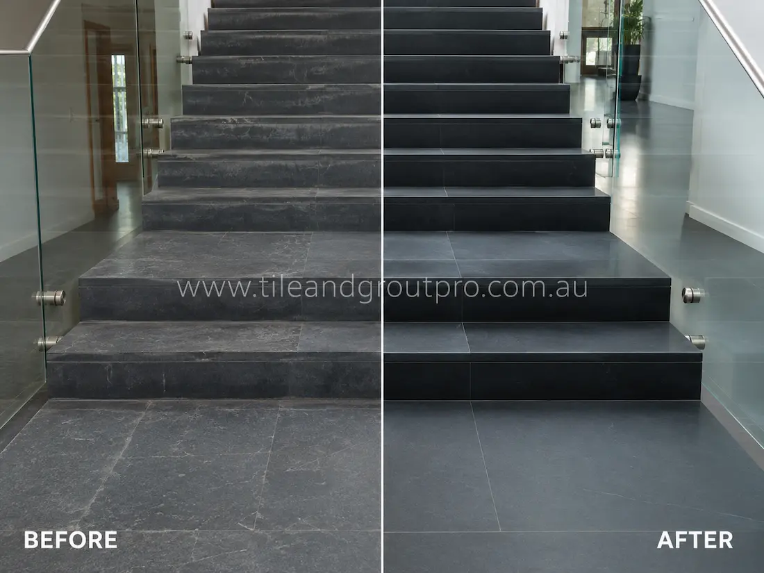 Indoor bluestone staircase tiles before grinding, featuring dull dark stone steps with surface wear, scuff marks, and faded texture beside modern glass balustrades.