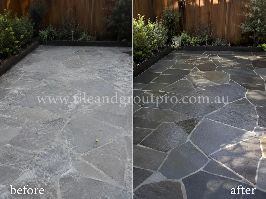 Before tile renewal, crazy paving bluestone tiles in a landscaped garden courtyard appeared faded and chalky with heavy surface wear and dull natural stone texture throughout the outdoor area.