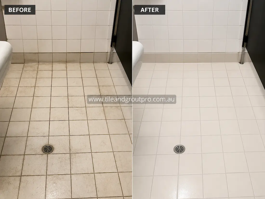 Before tile renewal, a commercial bathroom floor with white ceramic tiles and grout lines showed embedded dirt, staining, and discoloration around the drain and perimeter edges, resulting in a dull, worn appearance.