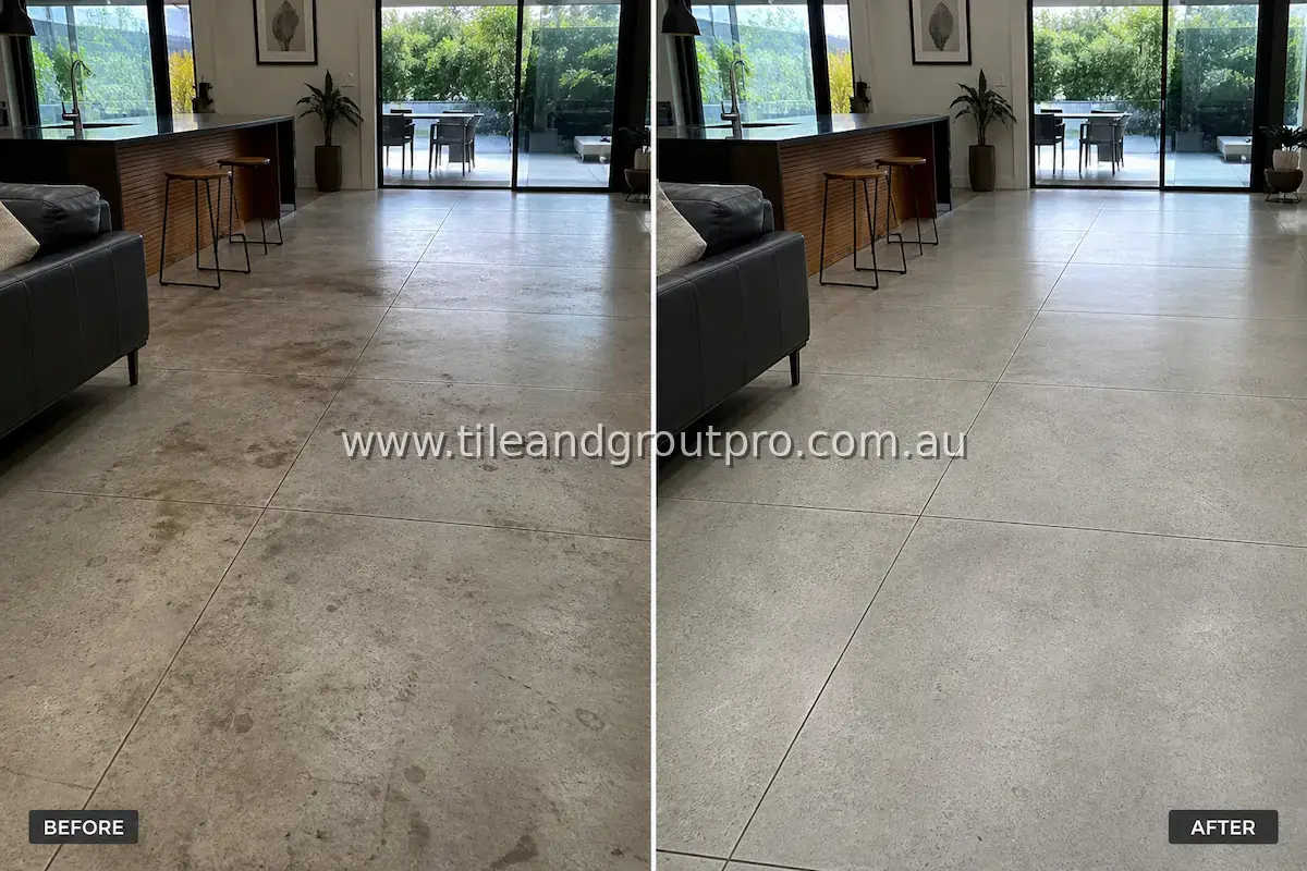 Concrete-look porcelain tile floor in an open-plan living room and kitchen with visible dirt buildup, stains, and dull surface before professional tile and grout cleaning