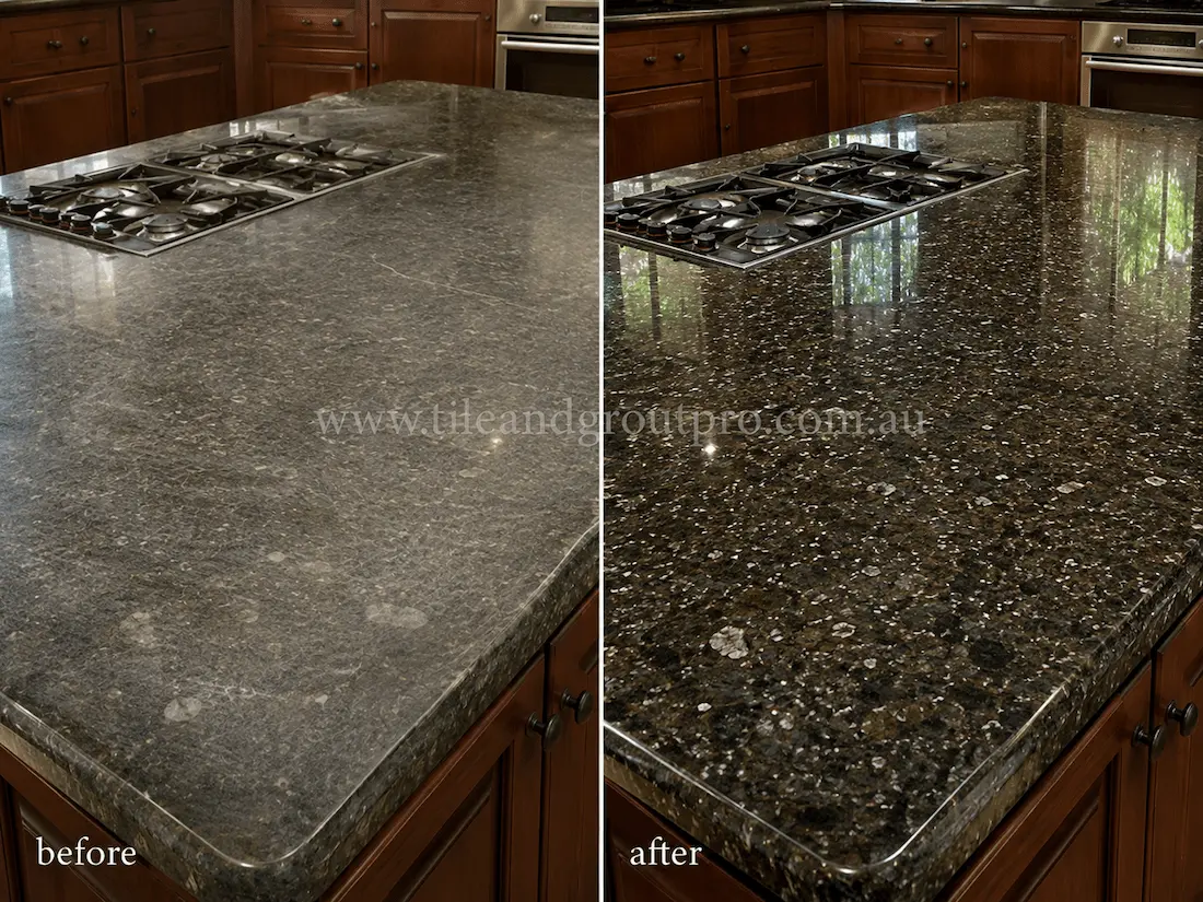 Residential kitchen island featuring a black granite countertop and built-in cooktop, showing dull wear patterns, etching, and loss of gloss before resurfacing.