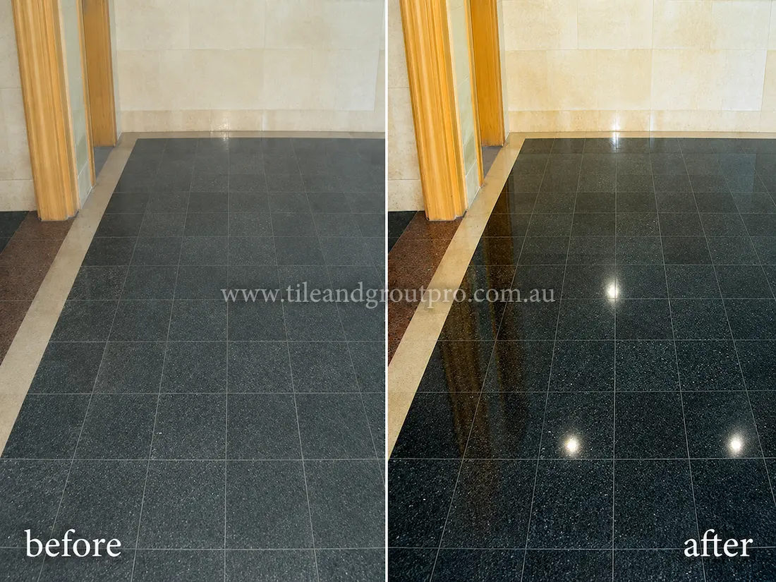 Before stone polishing, the black granite lift lobby floor tiles appeared matte and worn with reduced shine in a commercial building entrance with timber elevator surrounds.