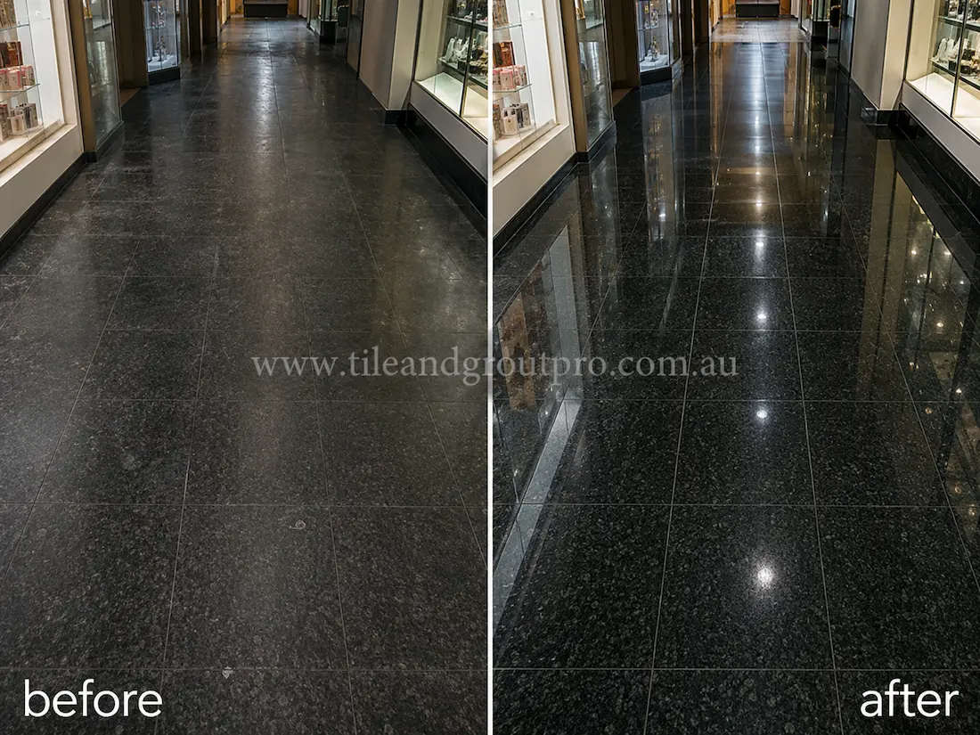 Before stone polishing, the black granite hallway floor tiles looked faded and scratched with limited reflection in a commercial shopping centre corridor lined with display windows.