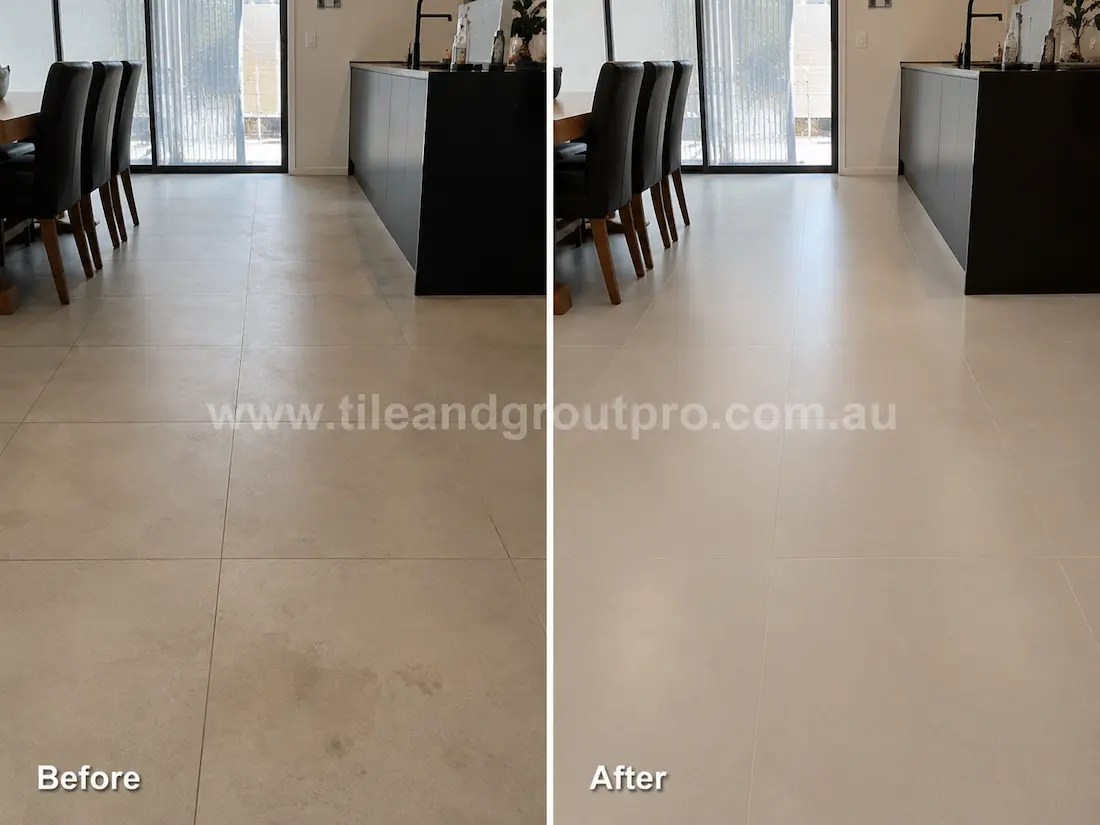 Before tile renewal, large-format porcelain floor tiles in an open-plan dining and kitchen area showed surface marks, light staining, and a faded finish that reduced the uniform appearance of the flooring.