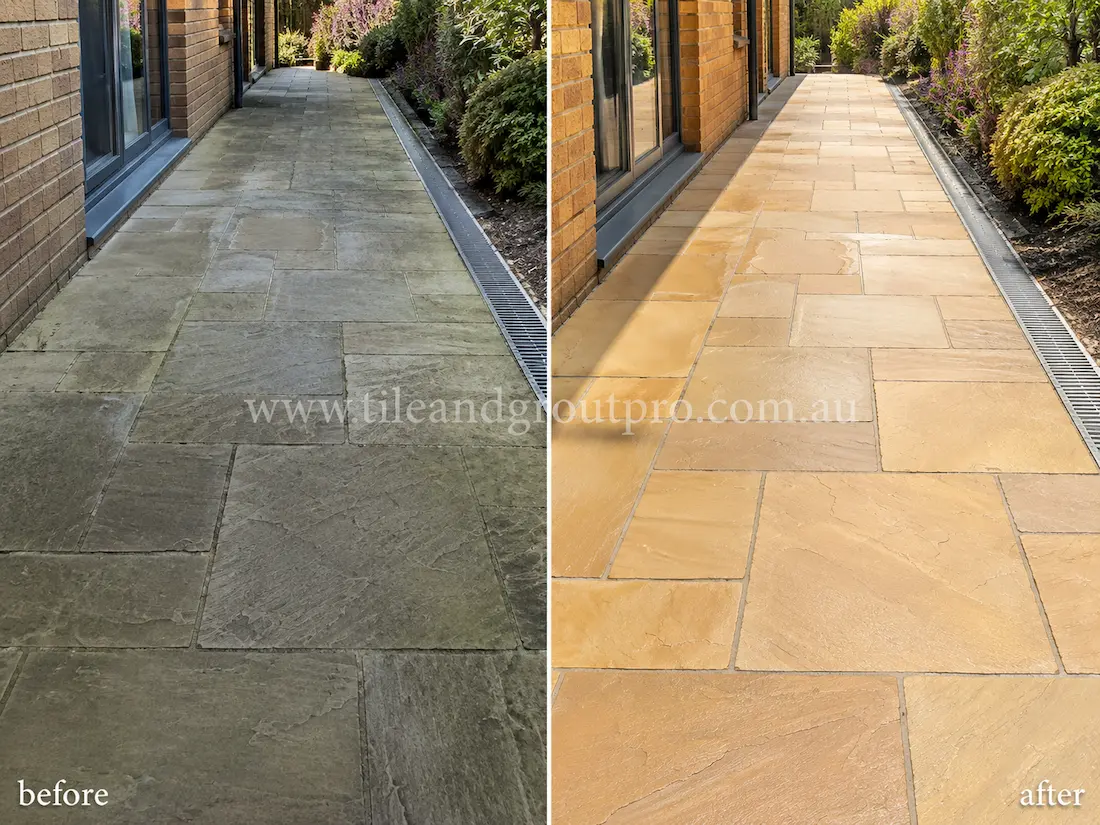 Before tile renewal, covered outdoor verandah sandstone tiles appeared faded and patchy with visible staining, grime buildup, and uneven stone colouring around wicker lounge furniture and potted plants.