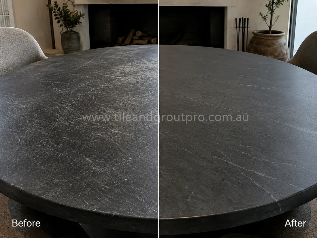 Round dark soapstone dining tabletop with heavy scratch marks before scratch removal in a modern dining room.