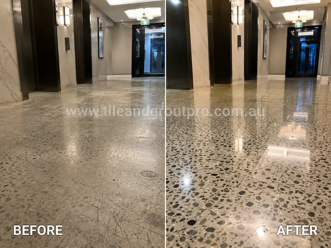 Commercial lobby terrazzo floor before grinding, featuring dull exposed aggregate flooring with visible scratches and worn polish near the lift entrance and hallway lighting.