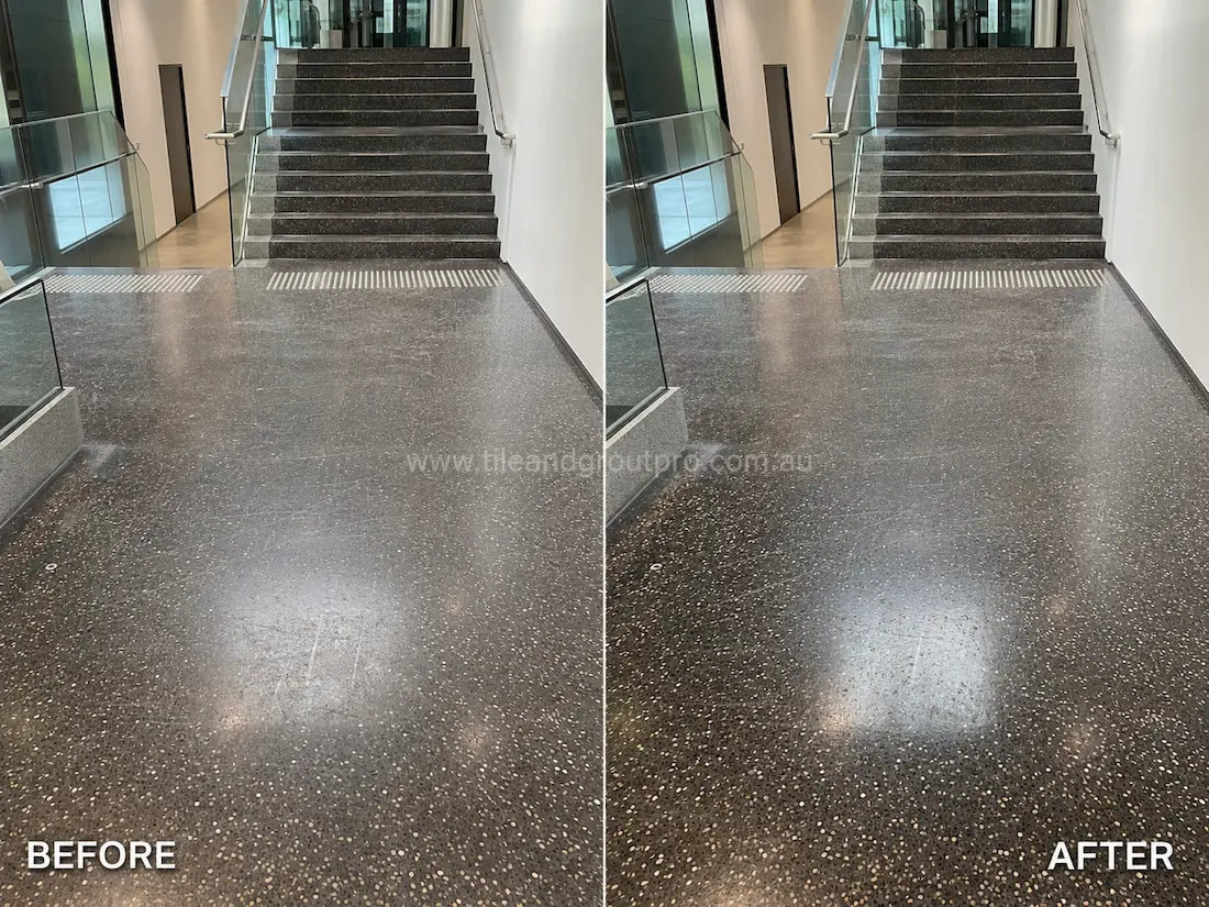 Modern office staircase with black terrazzo flooring before grinding, displaying surface scratches, scuff marks, and reduced gloss on the landing and stair treads.