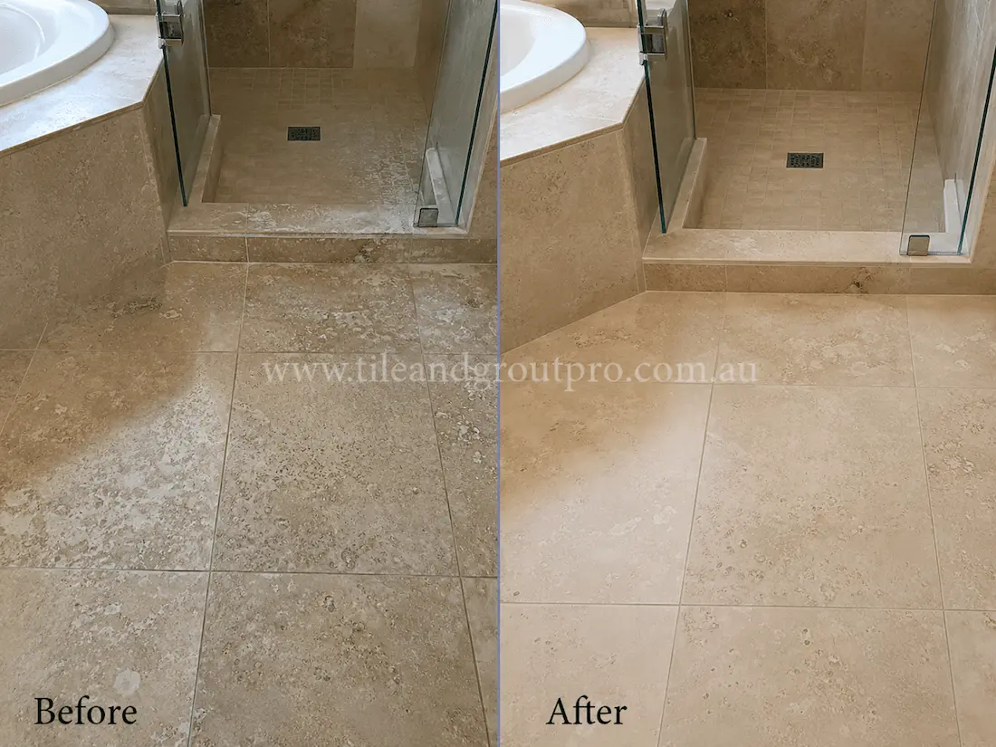 Travertine bathroom floor and shower entrance with etched stone, mineral deposits, and a dull worn appearance before tile resurfacing and polishing.